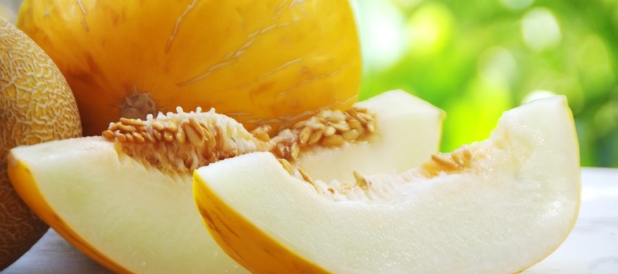 Melão fresco inteiro e cortado ao meio destacando a polpa suculenta e os benefícios do melão para a saúde.